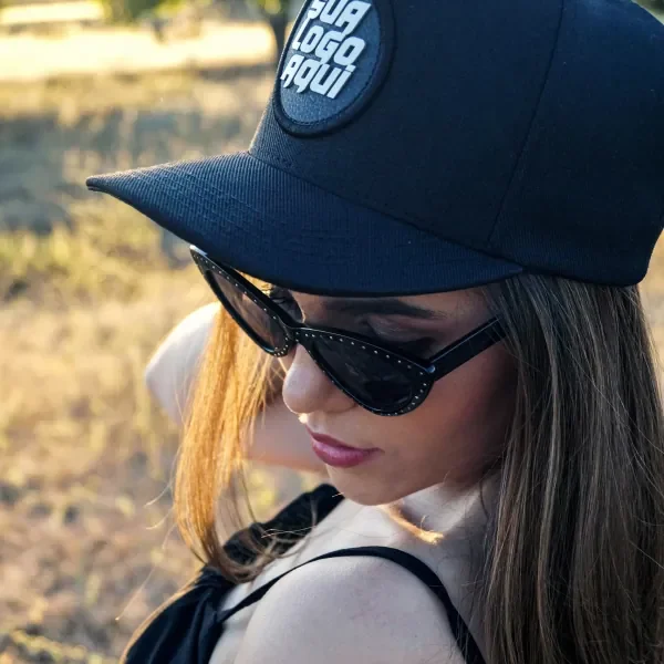 Mulher de óculos escuros usando boné preto com patch redondo para a sua logo